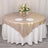 Elegant round table set with beige tablecloth, floral centerpiece, and dinnerware.