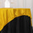Gold glitter tablecloth draped over a black table with napkin and glasses.