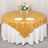 Gold tablecloth with elegant floral centerpiece and dinnerware on a round table.