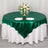 Round green tablecloth with white draping, set for dining with floral centerpiece.