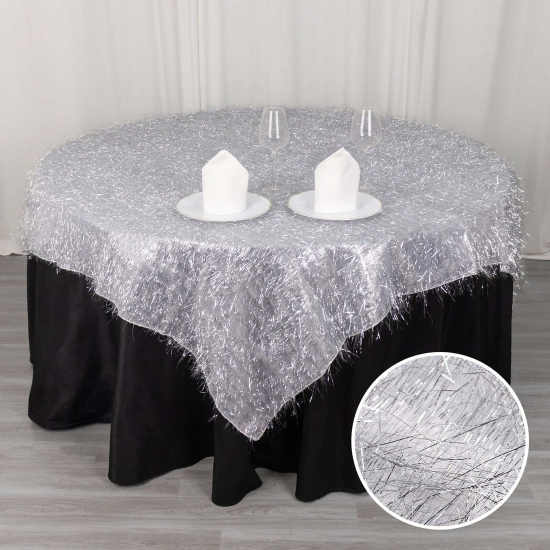 Silver tinsel table overlay with black tablecloth and decorative candles.