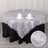 Silver tinsel table overlay with black tablecloth and decorative candles.