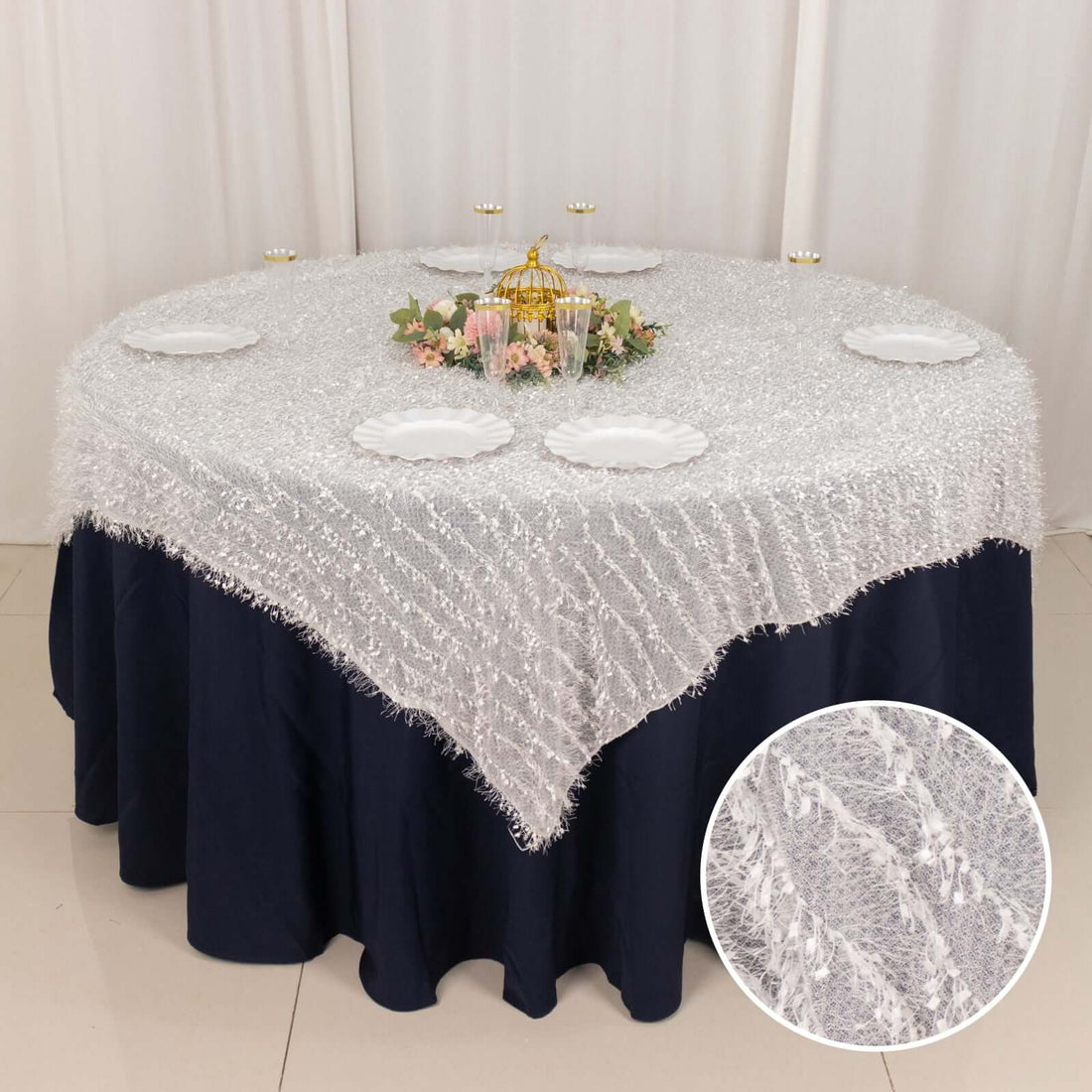 Elegant round table set with a white textured tablecloth and decorative centerpiece.
