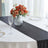 Elegant table setting with a black table runner and floral centerpiece.