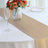 Elegant gold table runner on a white table with floral centerpiece.