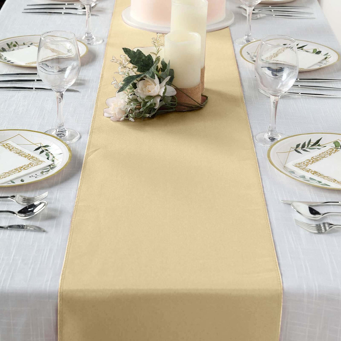 Elegant gold table runner on a decorated dining table with plates and candles.