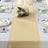 Elegant gold table runner on a decorated dining table with plates and candles.