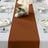 Brown table runner on a dining table set with plates and candles.