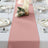 Table runner in blush pink on elegantly set dining table with candles and floral arrangement.