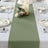 Olive green table runner on a dining table set with plates and candles.