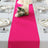 Bright pink table runner on a beautifully set dining table with floral accents.
