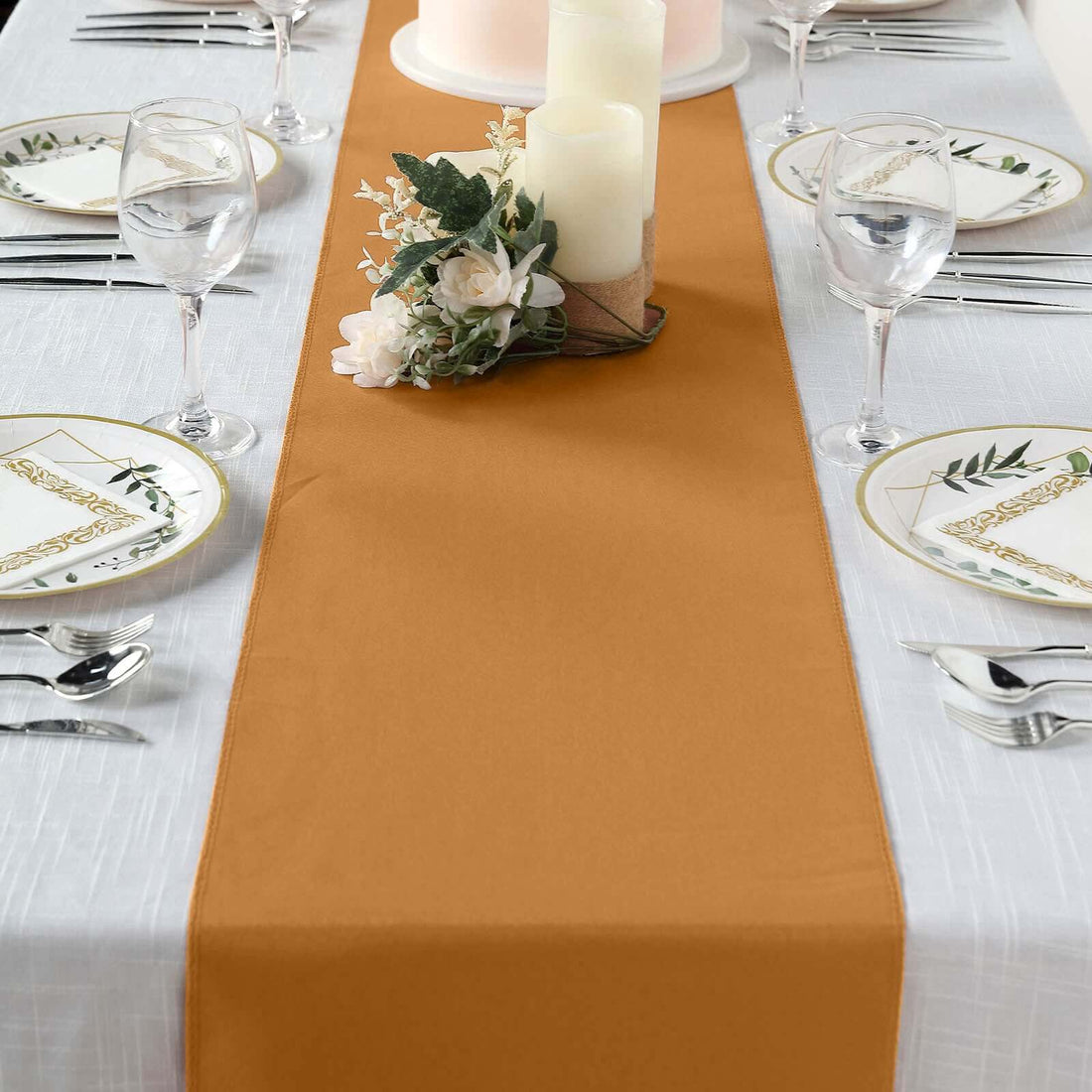 Table runner in warm gold color, styled with candles and floral decor on a dining table.