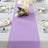 Lavender table runner on a dining table with elegant plates and candles.