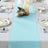 Turquoise table runner on a dining table with elegant plates and decor.