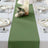 Green table runner on a beautifully set dining table with floral accents.
