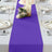 Purple table runner on a dining table set with plates and candles.