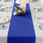 Blue table runner on a white table with elegant dinnerware and floral decor.