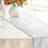 Silver table runner on a dining table with floral centerpiece.
