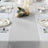 Elegant gray table runner with decorative plates and floral centerpiece on a dining table.