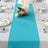 Turquoise table runner on a dining table with elegant table settings.