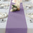 Purple table runner on a dining table set for a meal with floral accents.