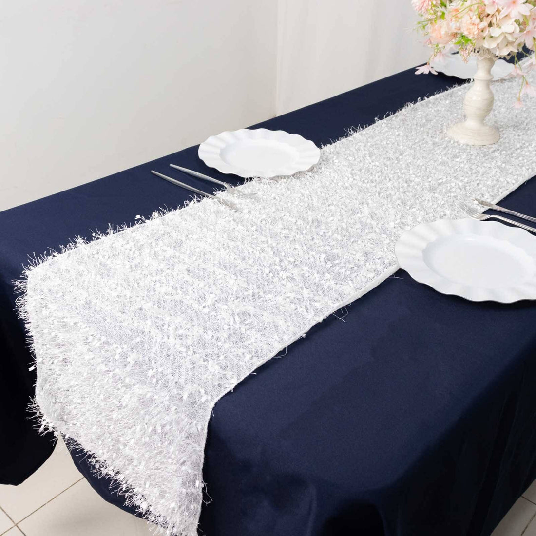 White textured table runner on a navy tablecloth with plates.