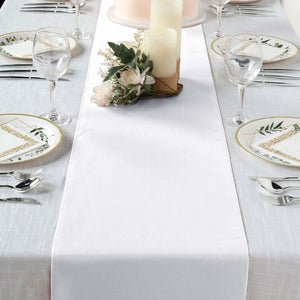 Elegant white table runner with candles and floral decor on a dining table setting.