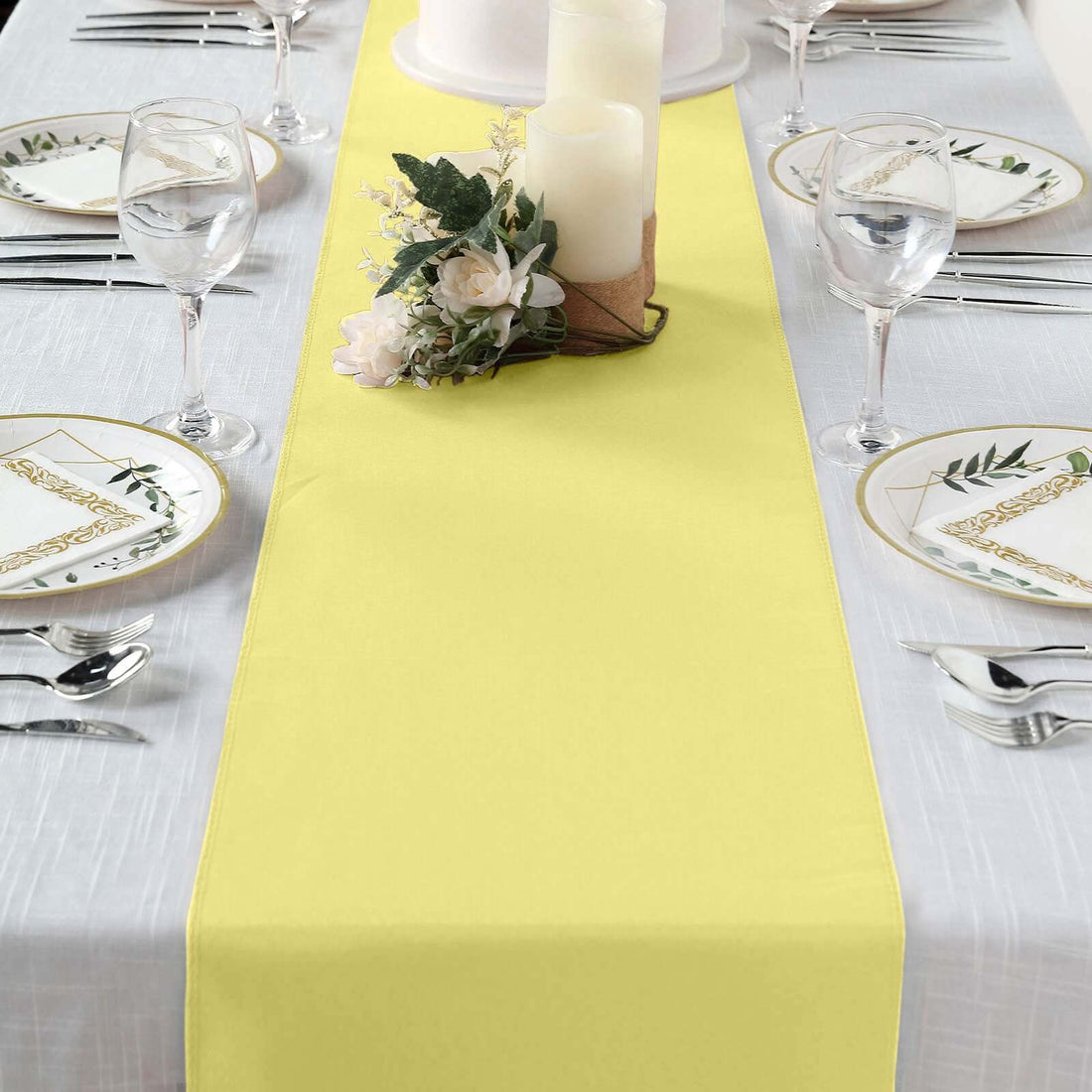 Yellow table runner on a set dining table with candles and floral decor.