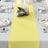 Yellow table runner on a set dining table with candles and floral decor.