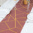 Geometric patterned table runner in burgundy and gold on a dining table.