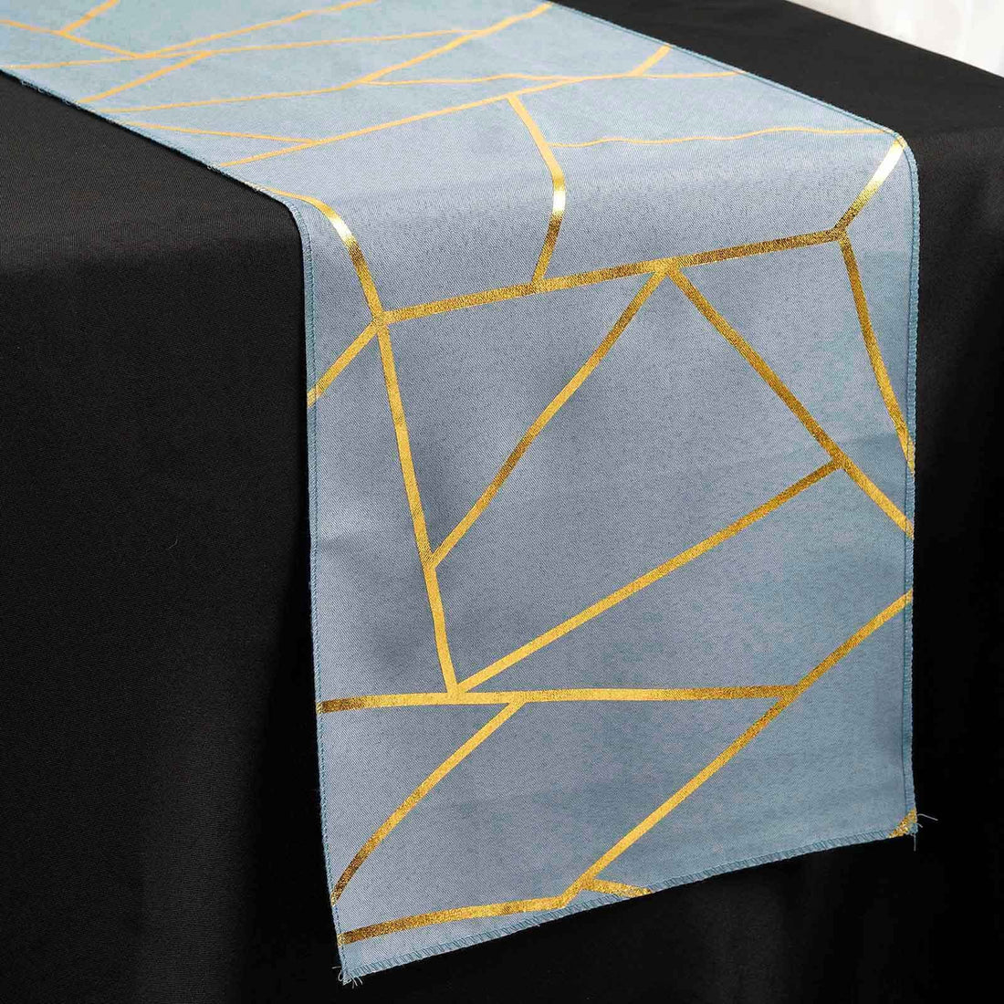 Blue table runner with gold geometric pattern on a black table.