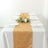 Elegant table setting with gold runner, plates, and floral centerpiece.