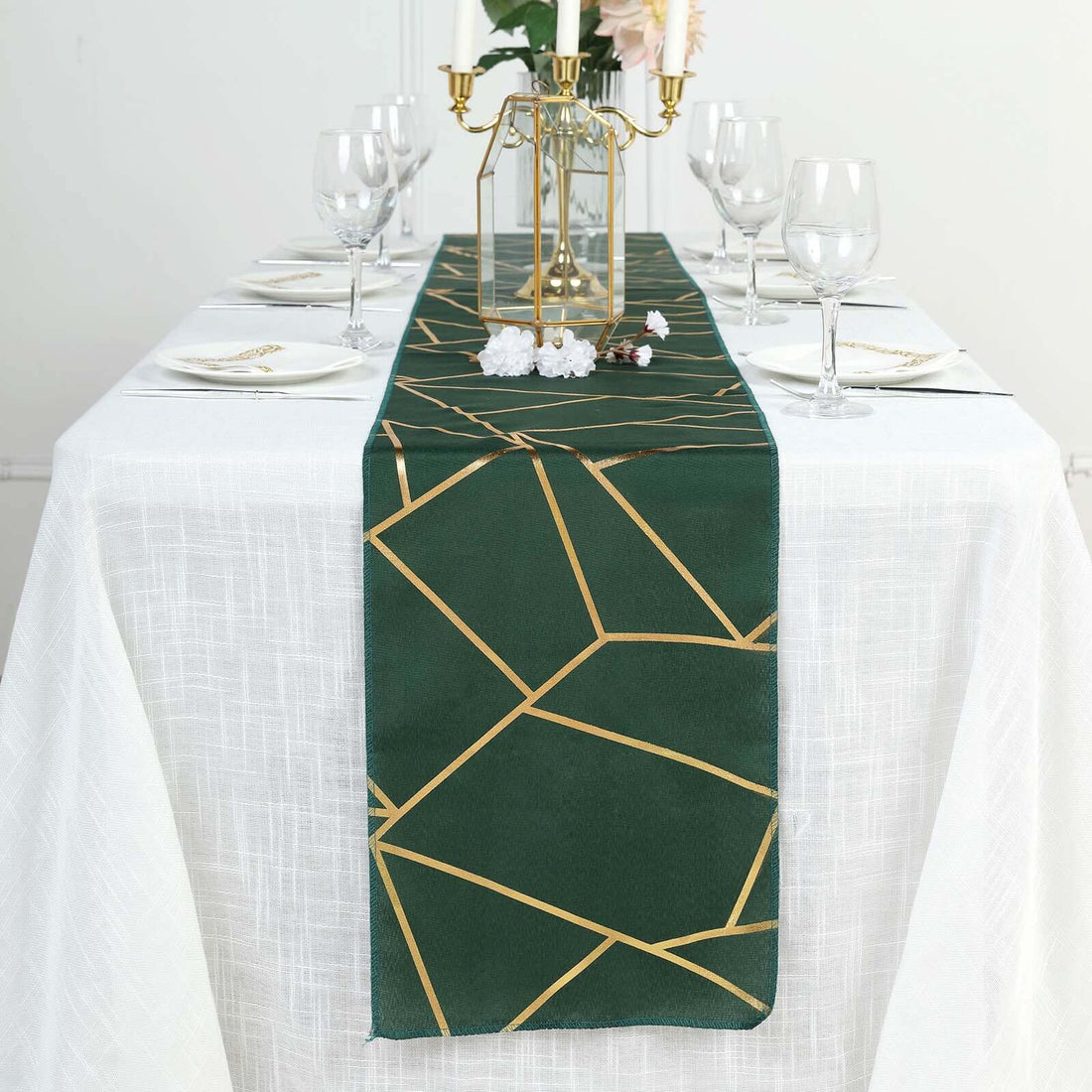 Green geometric table runner on a dining table set with glassware and candles.