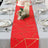 Red table runner with gold geometric design on a dining table setting.