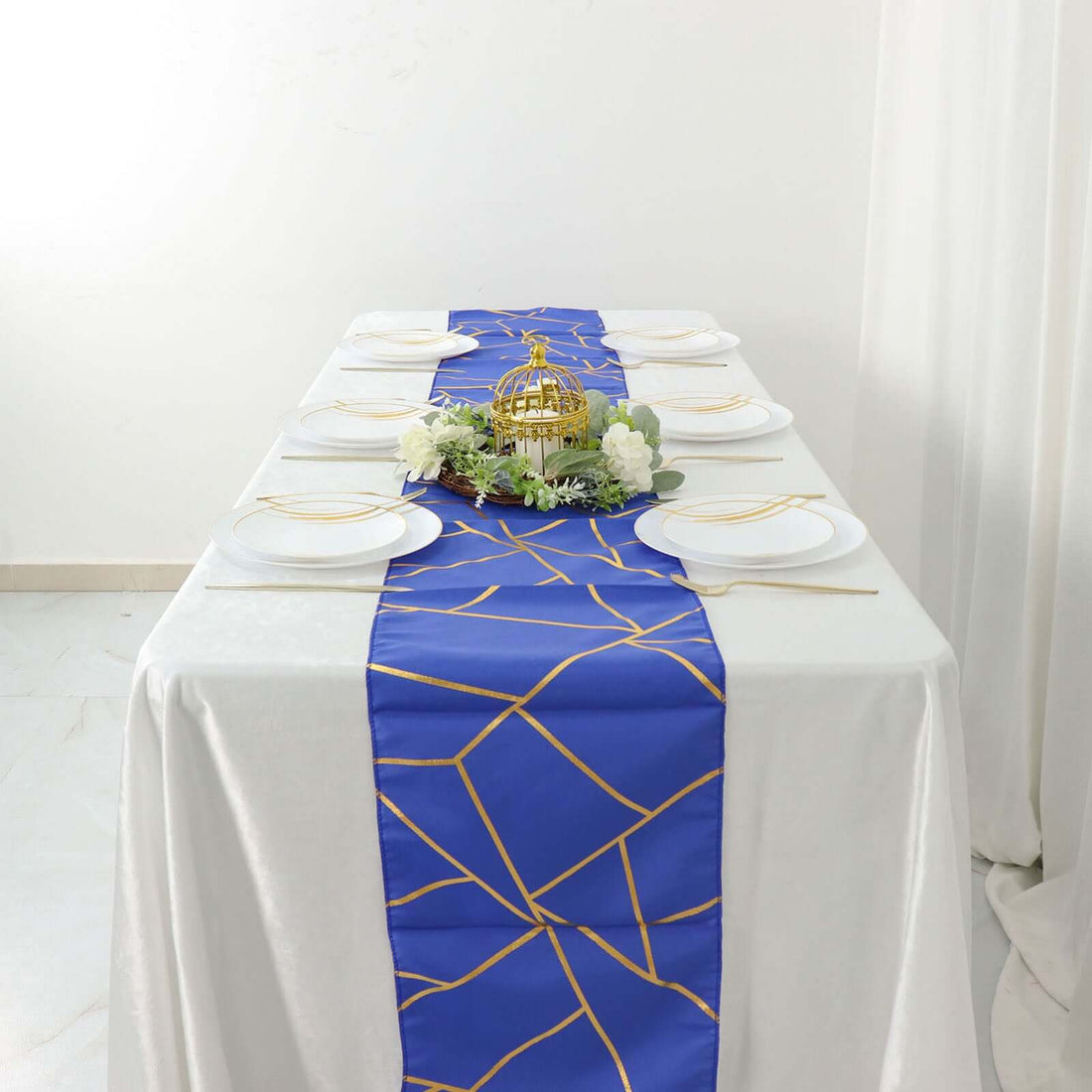 Elegant blue table runner with gold geometric design on a white table setting.