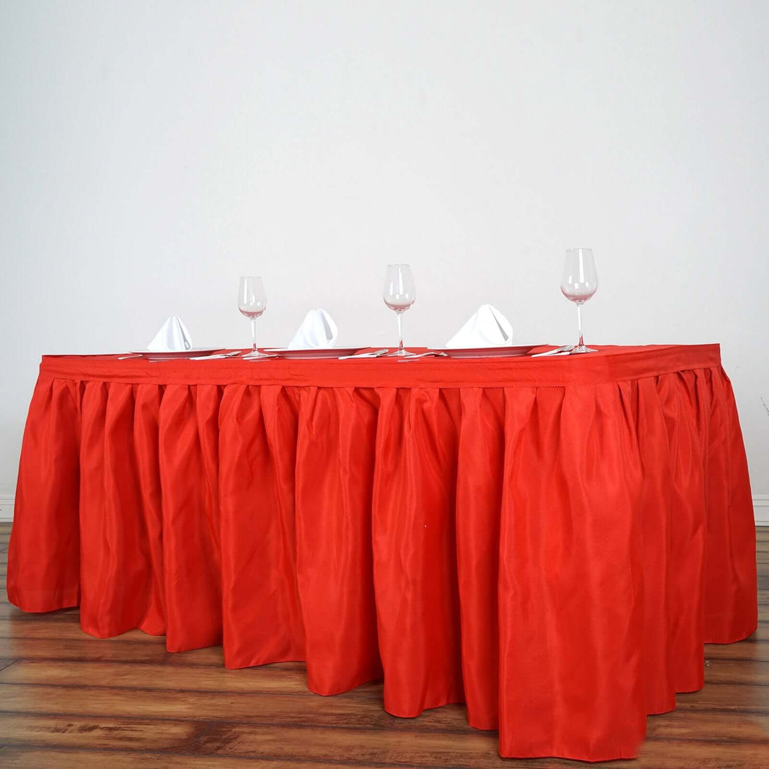 Red table skirt with glasses set for dining.