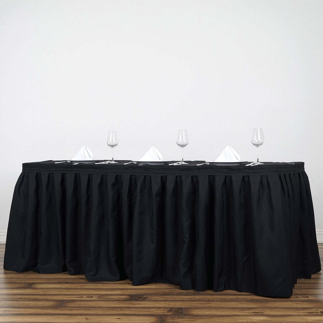 Black tablecloth draped over a long table set for dining with glasses and napkins.
