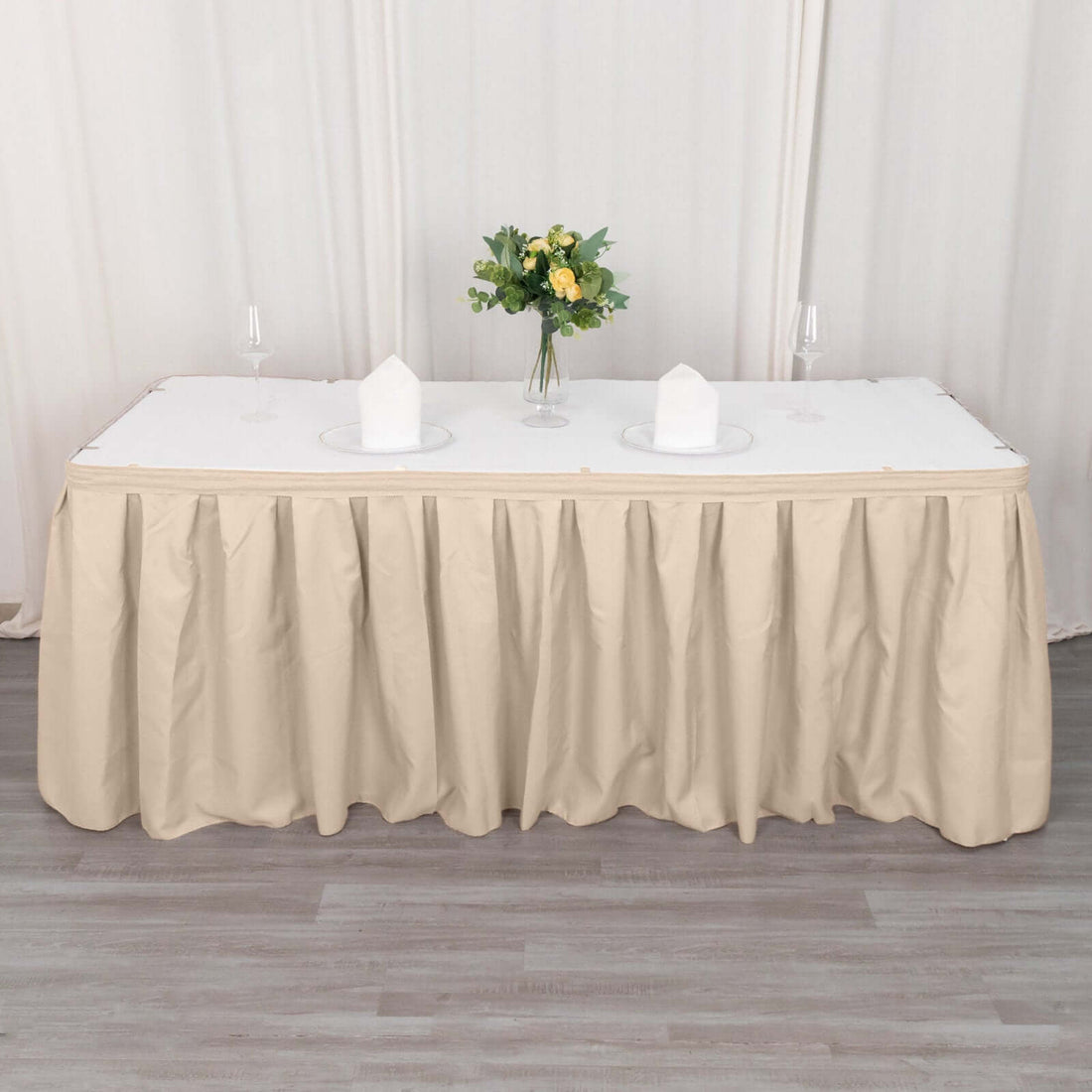 Beige tablecloth draped over a long table with floral centerpiece and plates.