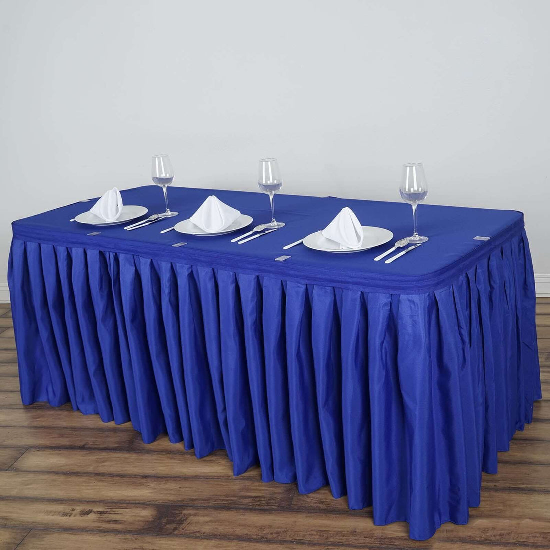 Blue tablecloth set with plates and glasses for elegant dining.