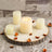 Set of decorative candles on a wood slice with dried petals.