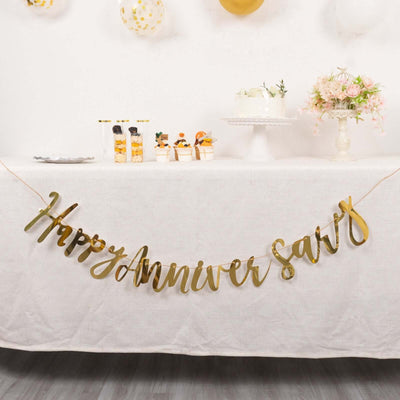 Gold "Happy Anniversary" banner at a festive table with treats and decorations.
