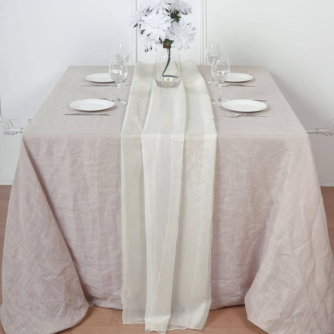 Elegant table setting with cream table runner, plates, and glassware.