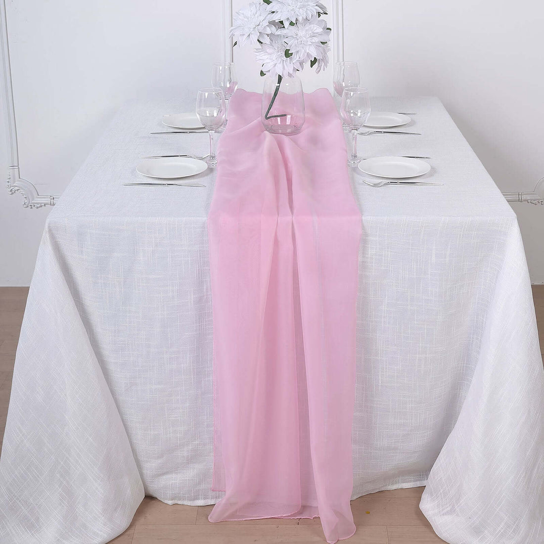 Pink chiffon table runner draped elegantly on a white tablecloth.