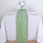 Green table runner on a white table set for dining with flowers and glassware.