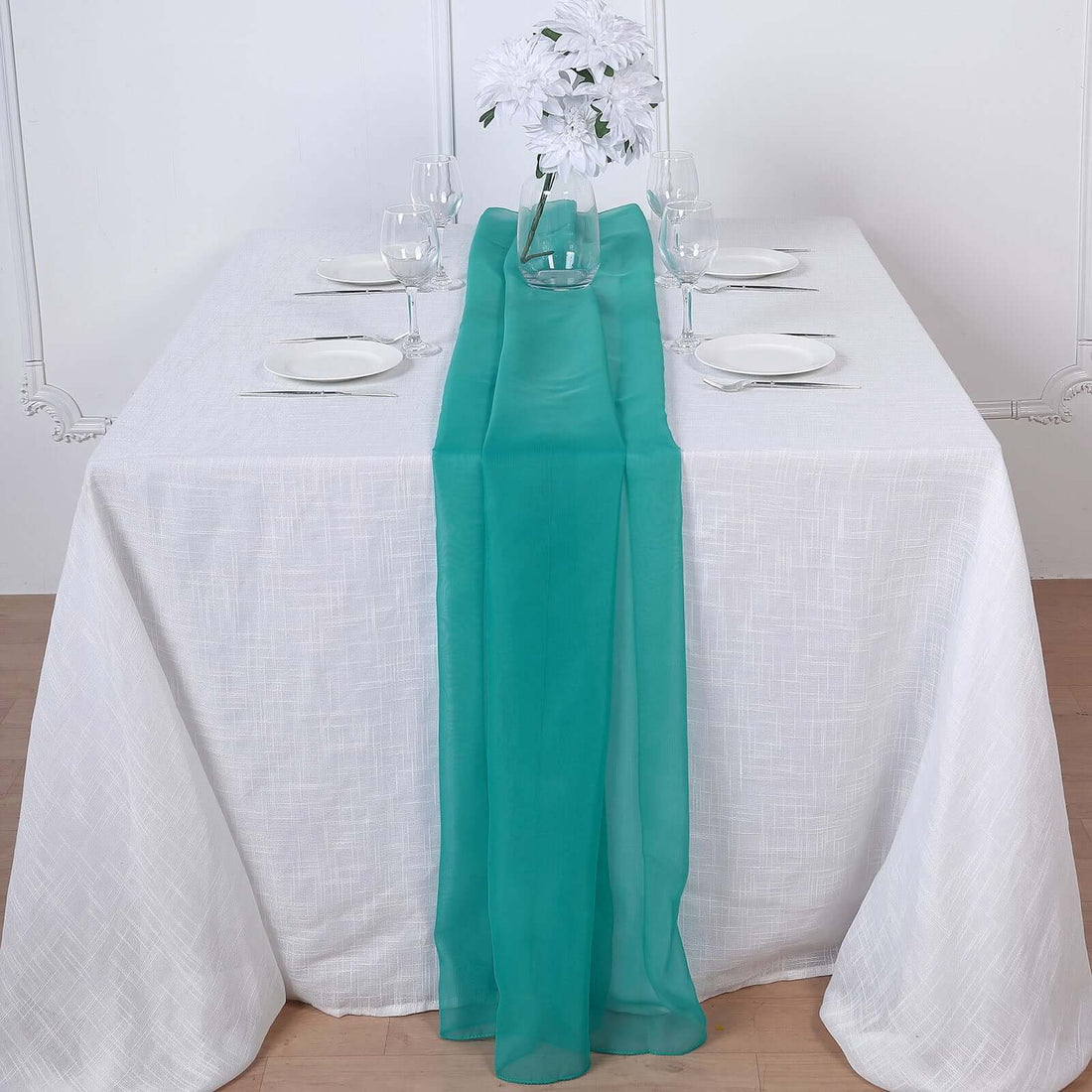 Teal table runner on a white table with plates and glasses.