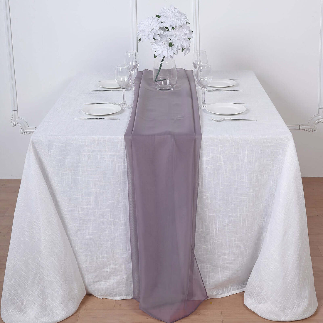 Elegant table setting with white linens and a sheer purple runner.
