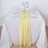 Yellow table runner on a white table setting with glassware and plates.