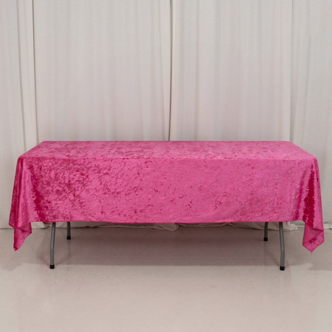 Pink velvet tablecloth on a folding table against a plain backdrop.