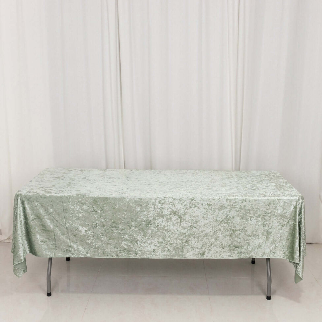 Green textured tablecloth draped over a table on a plain backdrop.