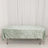Green textured tablecloth draped over a table on a plain backdrop.